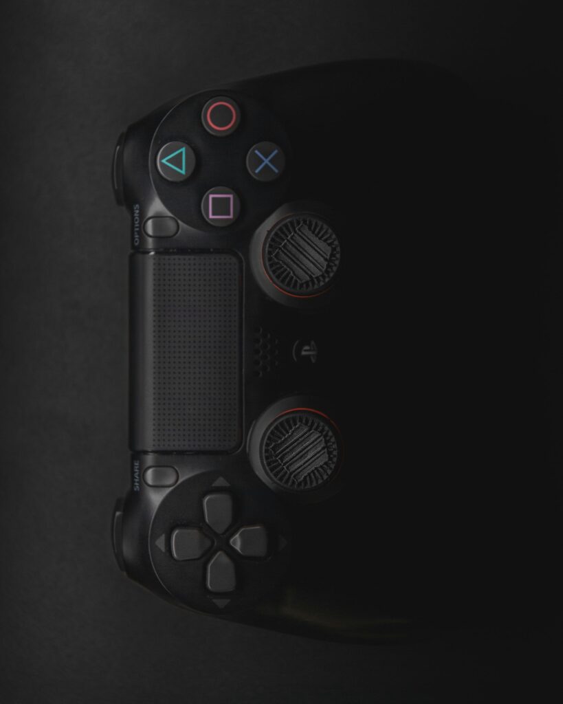 pexels-photo-1337247-1337247 Moody close-up of a black gaming controller in low light with colorful buttons.